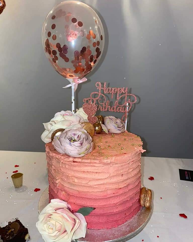 Celebration cake. Ombre effect of three different shades of rose gold building up with the colour going from light to dark, topped with flowers and macarons.