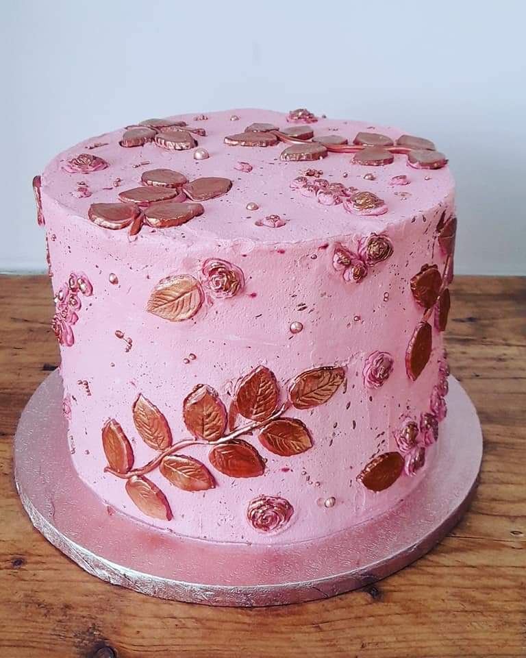 A eight inch rose gold vanilla buttercream cake filled with strawberry jam and vanilla buttercream.  Roses and flowers are handmade and painted to your desires.