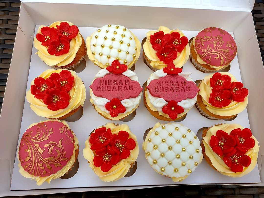 A box of twelve vanilla personalised decorative red and dusky pink cupcakes.